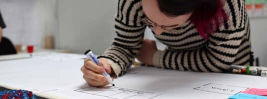 Student leaning over drawing on paper